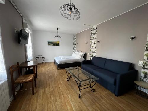 een woonkamer met een blauwe bank en een bed bij Hotel Les Montois in Céaux