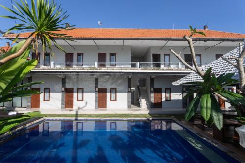a swimming pool in front of a building at Cempaka Mas Guest House Canggu in Canggu