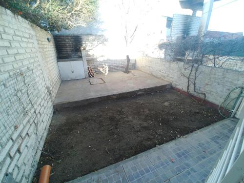 a backyard with a brick wall and a dirt yard at Ankara 1 in Las Grutas