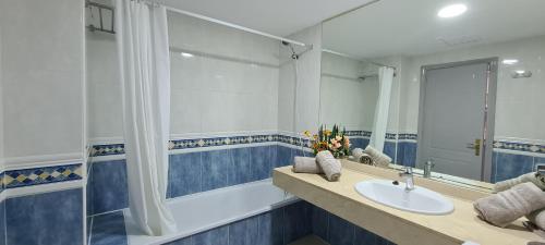 W łazience znajduje się umywalka, wanna i lustro. w obiekcie Beautiful garden flat nearly refurbished free WiFi w Corralejo