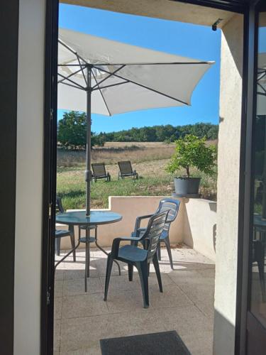eine Terrasse mit einem Tisch, Stühlen und einem Sonnenschirm in der Unterkunft la grange du château in Boissières