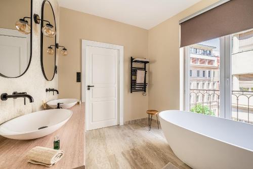 ein Badezimmer mit einer großen weißen Badewanne und einem Fenster in der Unterkunft Asboth Boutique Budapest in Budapest