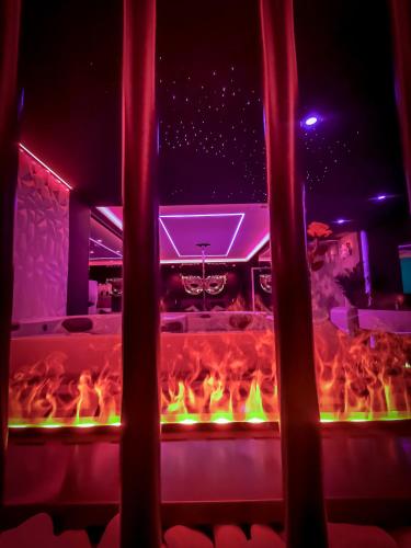 a fire pit in a room with red and green lights at LES SECRETS ROOMS, LOVE ROOM DE LUXE AVEC JACUZZI in Rivesaltes