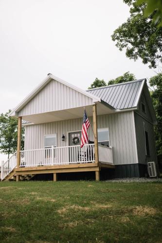 a large white house with a flag on a porch at Cozy Cottage on 250 Acre Dairy Farm Near Ark in Dry Ridge