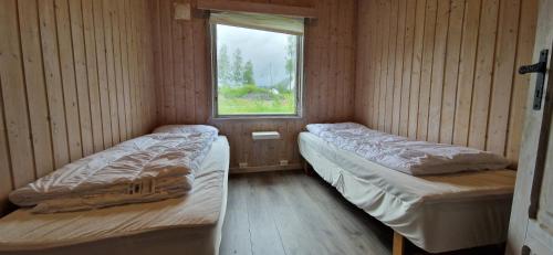 two beds in a small room with a window at Døskeland in Sande