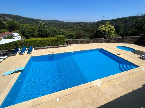 a swimming pool in a yard with chairs at Quinta de Mourães Casa dos Rododendros in Lever