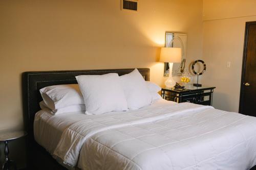 um quarto com uma cama com lençóis brancos e almofadas em Hotel Fray Marcos em Nogales