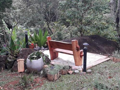 a wooden bench sitting in the middle of a garden at Pousada Estância Rio Acima in Itamonte