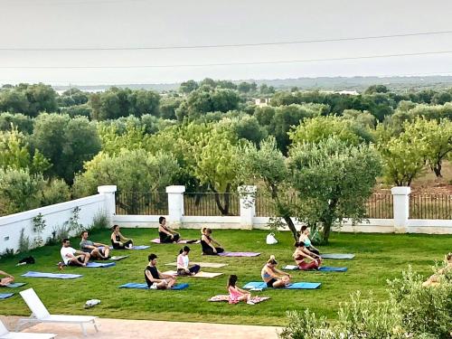a group of people doing yoga in the grass at Tenuta Amostuni-Country House in Ostuni