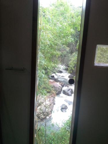 a door with a window looking out at a river at Pousada Estância Rio Acima in Itamonte