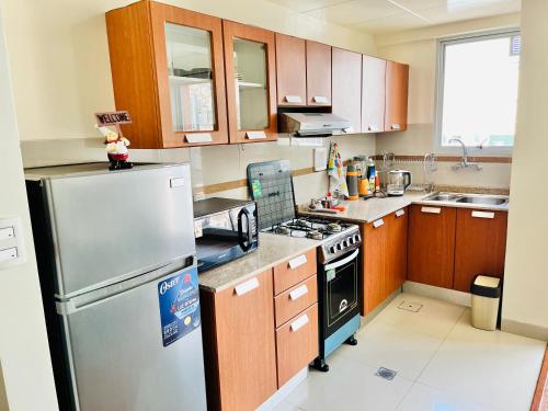 uma cozinha com armários de madeira e um frigorífico de aço inoxidável em Moderno y Cómodo Apartamento con la Mejor Ubicación en Sopocachi em La Paz