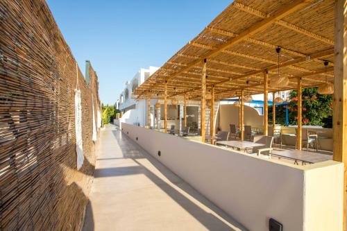 an outdoor patio of a building with tables and chairs at Atma Beach Rooms & Suites in Faliraki