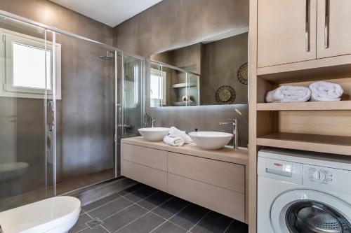 a bathroom with two sinks and a washing machine at Ninemia Villa in Skopelos in Skopelos Town