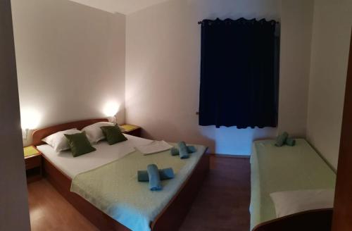 sypialnia z 2 łóżkami i zielonymi poduszkami w obiekcie Apartments Sretna w Gradacu