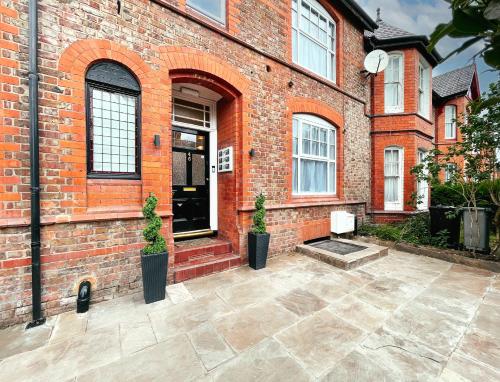 a brick building with two potted plants in front of it at Ashfield Boutique Stays in Altrincham