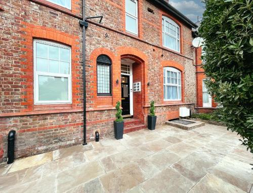 a brick building with two potted plants in front of it at Ashfield Boutique Stays in Altrincham