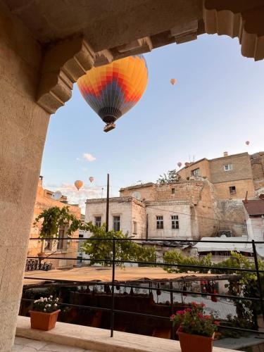 a hot air balloon flying in the sky over a city at Kaya Konak Cave in Nevsehir