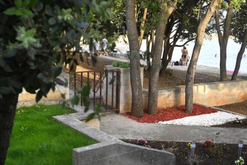 a park with trees and red flowers in the grass at Apartment by the sea Renata in Punta Skala in Petrcane
