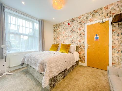 a bedroom with a bed with yellow pillows and a window at Ashfield Boutique Stays in Altrincham