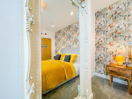 a bedroom with a yellow bed and a mirror at Ashfield Boutique Stays in Altrincham