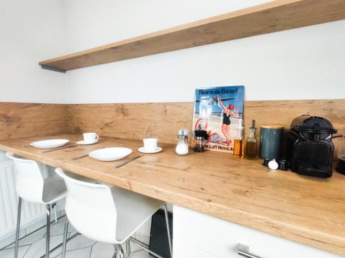 een houten aanrecht met witte stoelen in een keuken bij INIKAMA: Designer Apartment im Grünen – Netflix in Rosengarten