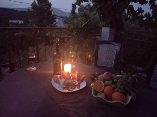una mesa con una botella de vino y un plato de fruta en apartmani ANITA, Korčula, en Korčula