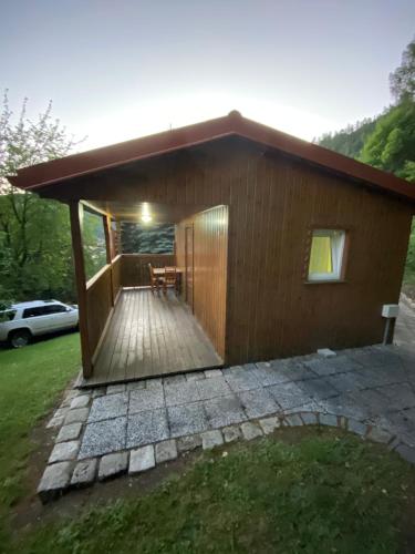 a small house with a deck with a car parked at Selský Dvůr Perštejn in Pürstein