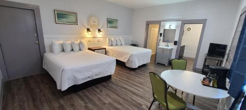 a hotel room with two beds and a table at Outer Banks Motor Lodge in Kill Devil Hills