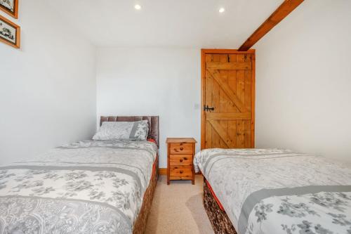 a bedroom with two beds and a wooden door at Knott View in Milnthorpe