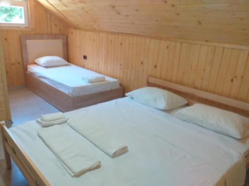 a room with two beds in a wooden cabin at Bujtina Arlindi in Valbonë
