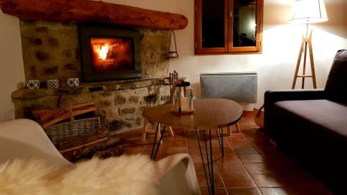 a living room with a fireplace and a table and a couch at La Louronnaise in Bordères-Louron