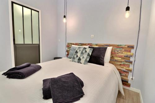 una camera da letto con un grande letto bianco con cuscini di La Sardine du Panier® a Marsiglia