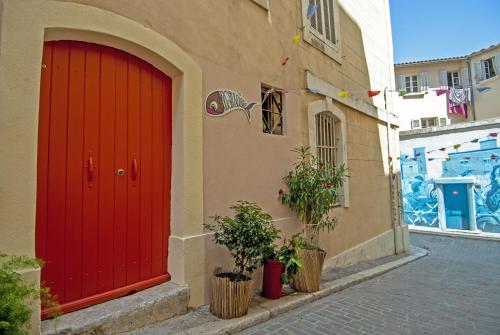 a red door on the side of a building with plants at La Sardine du Panier® in Marseille