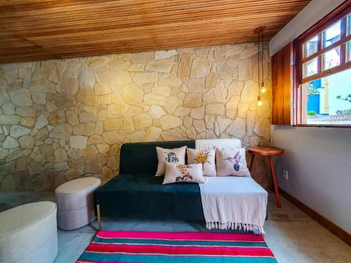 een kamer met een groene bank en een stenen muur bij Casita Amarela na rua mais charmosa de Mucugê - BA in Mucugê
