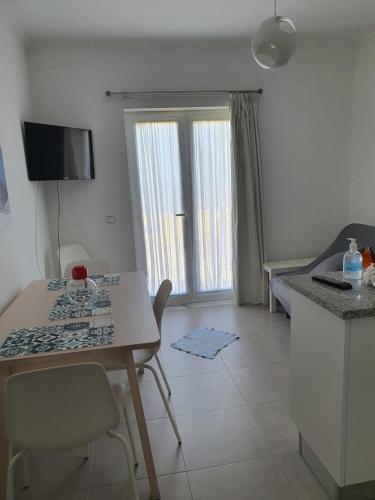 a living room with a table and a room with a bed at Apartamento Sol e Mar Sesimbra in Sesimbra