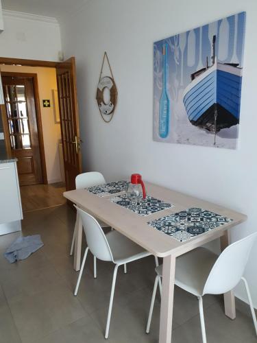 a dining room table with white chairs in a room at Apartamento Sol e Mar Sesimbra in Sesimbra