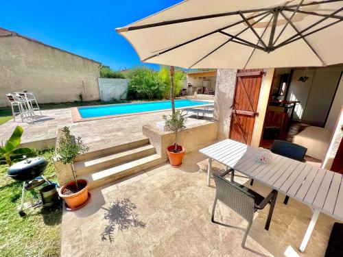 洛爾格的住宿－Studio avec jacuzzi et piscine，一个带桌子和遮阳伞的庭院和一个游泳池