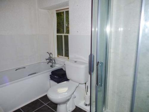 a white bathroom with a toilet and a bath tub at Woodside Cottage in Snainton