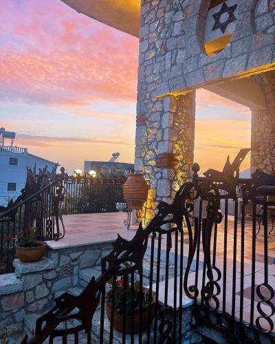 a fence in front of a building with a sunset at Solomon&Sons in Dhërmi