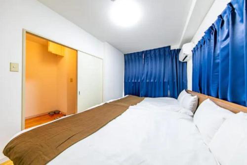 Un dormitorio con una cama grande con cortinas azules. en Ash Court Joto, en Osaka