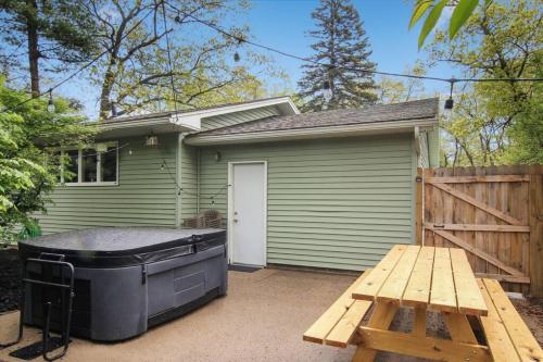 a small green house with a hot tub and a picnic table at 3 min to Beach, Game Room, Hot tub & Firepit in Traverse City