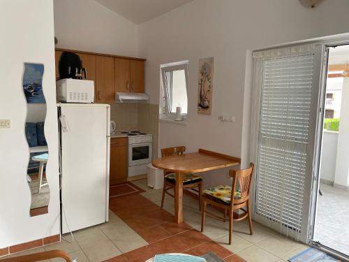 Il comprend une cuisine équipée d'une table et d'un réfrigérateur blanc. dans l'établissement Apartment Near The Beach, à Privlaka