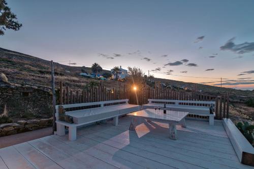 two benches and a table on a wooden deck at On The Rocks Antiparos in Antiparos Town