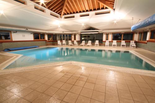 a large swimming pool in a building with chairs at Residenza Del Sole in Gressoney-Saint-Jean