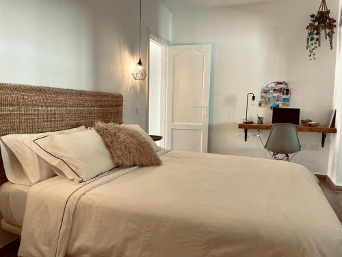 een slaapkamer met een groot bed met witte lakens en kussens bij Casa Armonía in Morro del Jable