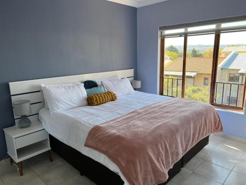 um quarto com uma cama grande e uma janela grande em Relaxing Getaway in Waterfall - close to Mall of Africa em Midrand