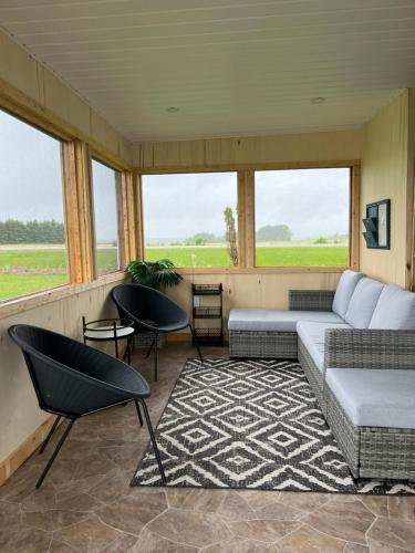 a living room with a couch and chairs and windows at Serendib by St Peters Bay in Saint Peters