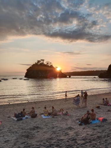 a group of people sitting on the beach at sunset at Agung Pring Homestay in Sampalan