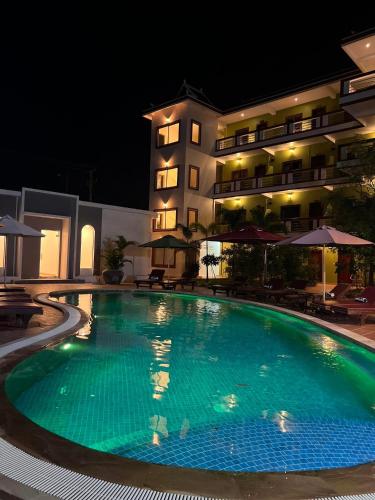 a swimming pool in front of a hotel at night at The Moon Kampot Boutique in Kampot