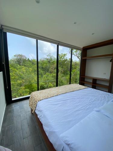 1 dormitorio con cama y ventana grande en Cuatro Elementos Noh, en Tulum